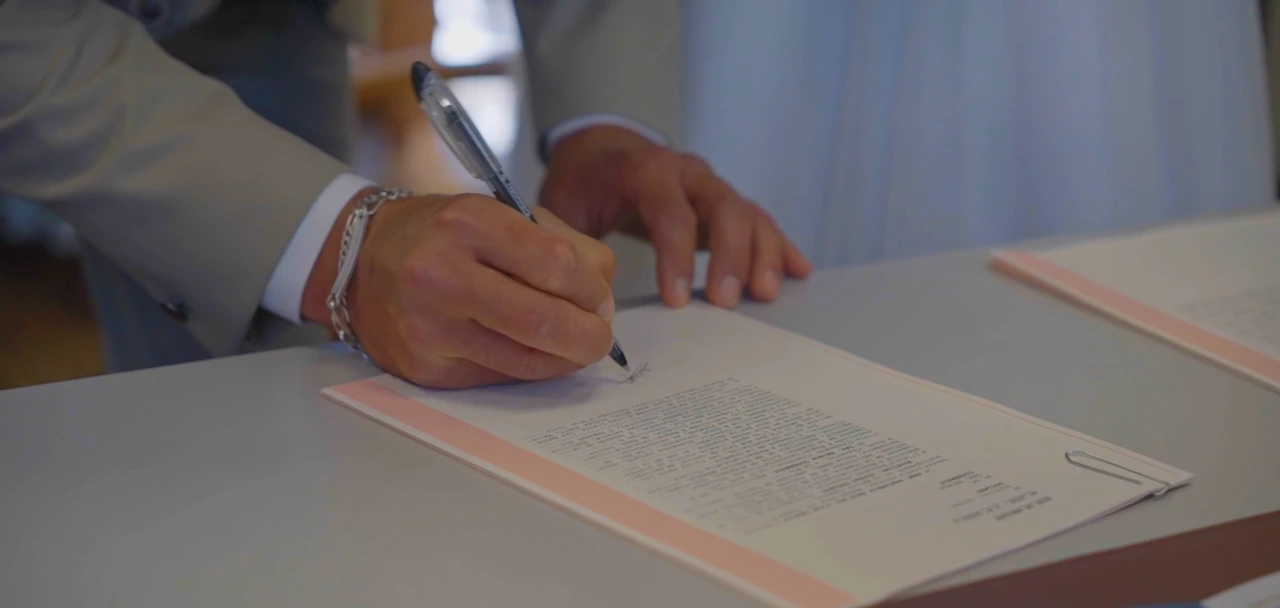 Les mains du marié signant le registre.
